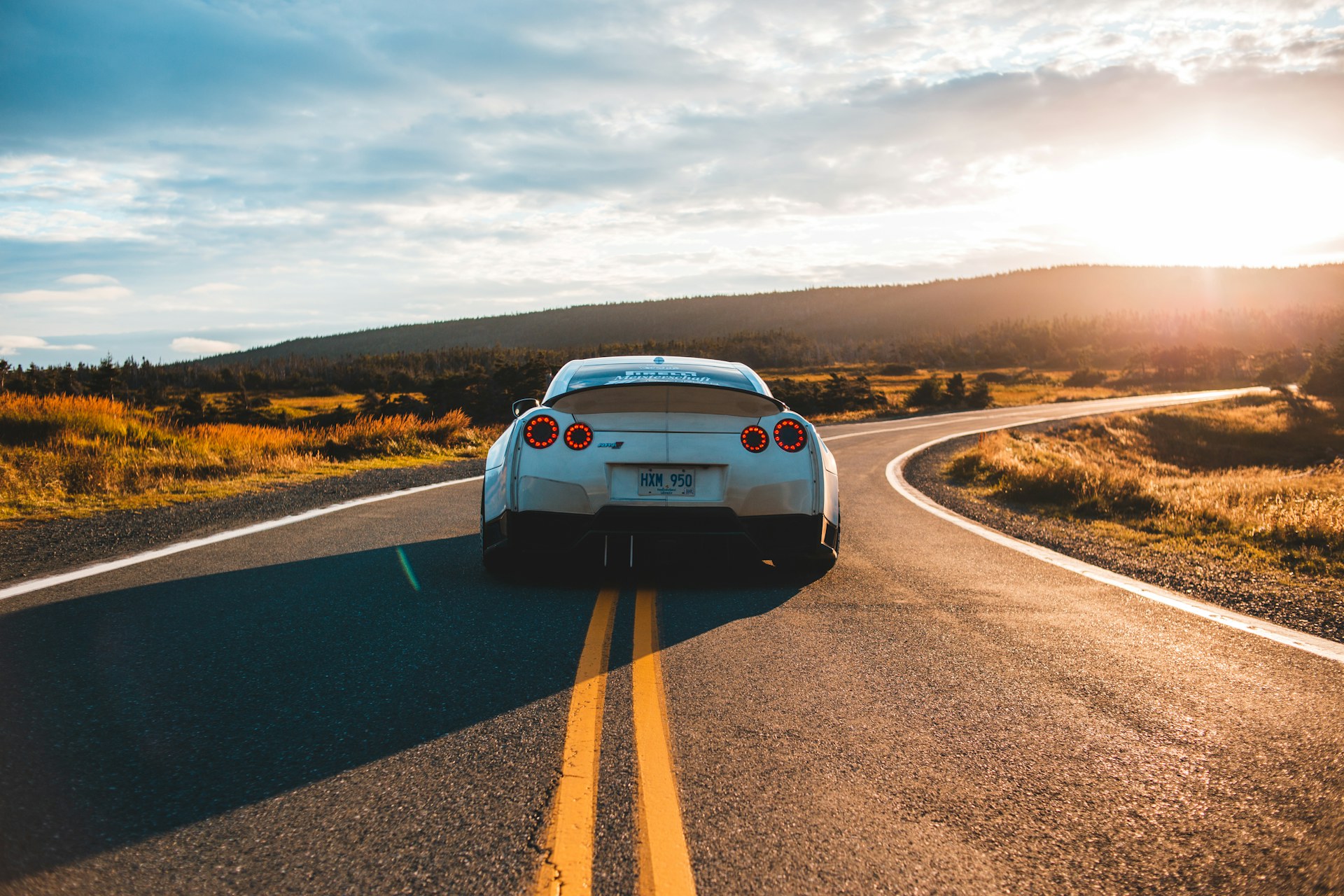 Auto sportiva su strada al tramonto in lontananza